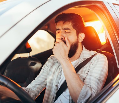 Ein Mann gähnt im Auto.